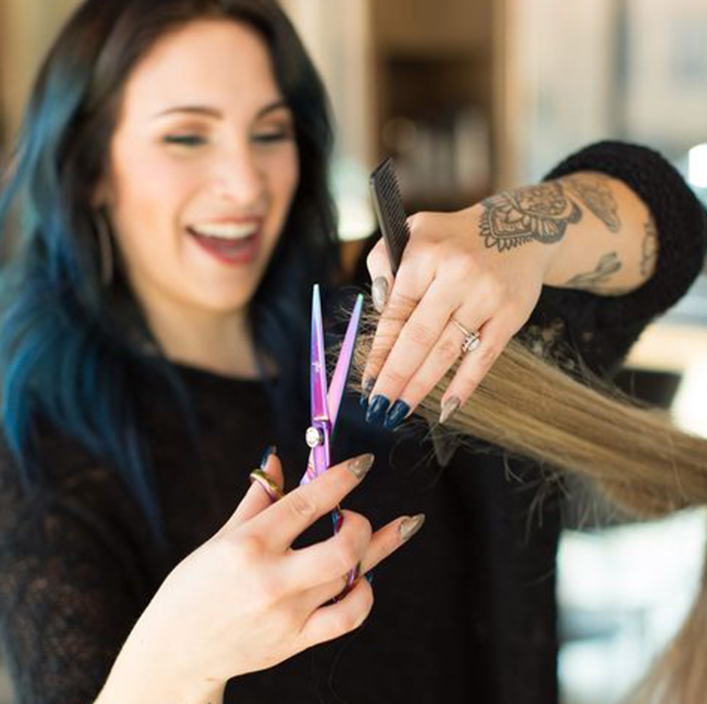 shears cutting hair in front of woman