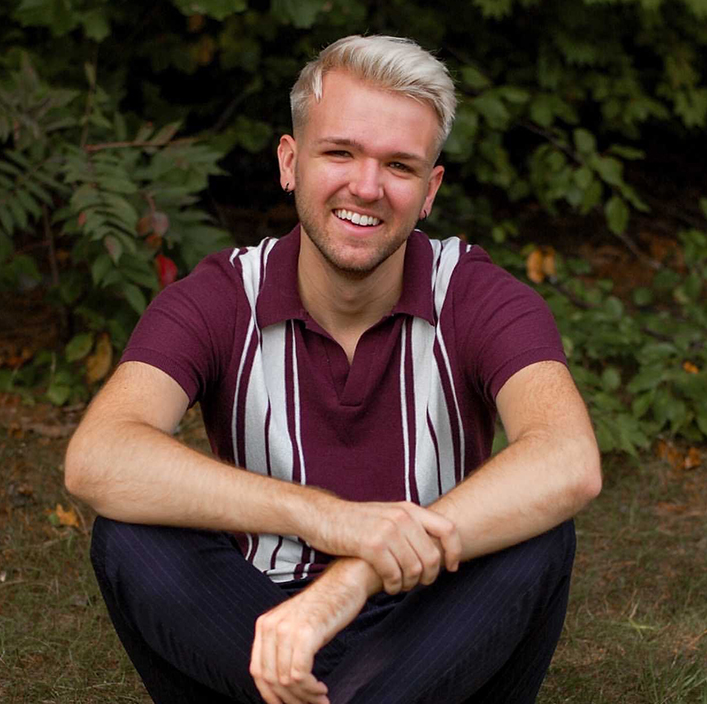 guy sitting down in striped polo and blonde hair